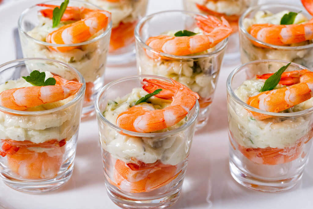 Individual shrimp cocktail shooters in a glass cup with homemade aioli sauce
