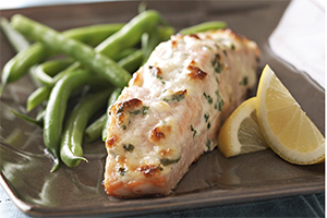 parmesan baked salmon with string beans and a lemon wedge on a plate